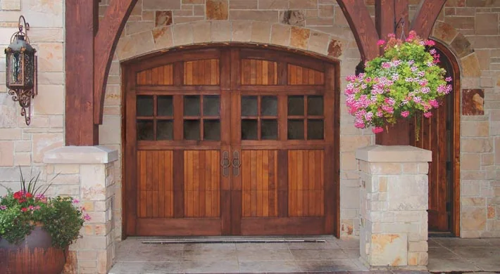 A wood carriage garage door with a stone surround and planters
