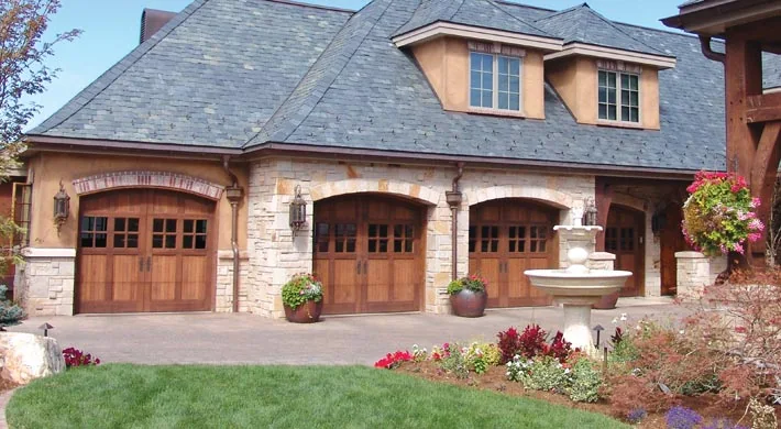 Two arched wood garage doors on a yellow stucco home