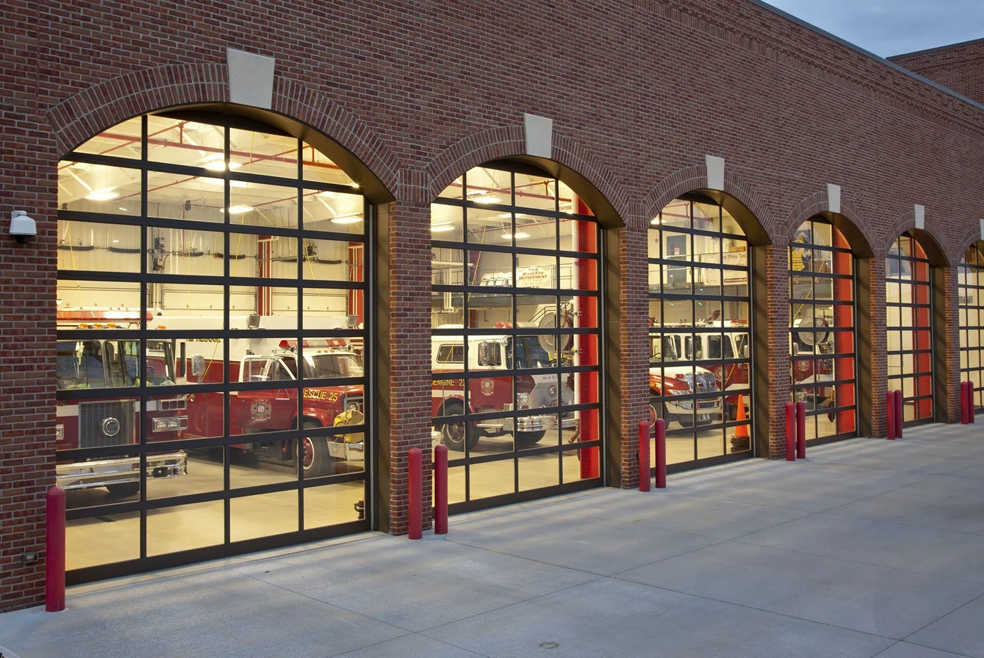 Arched full view glass bay doors on a fire station at night