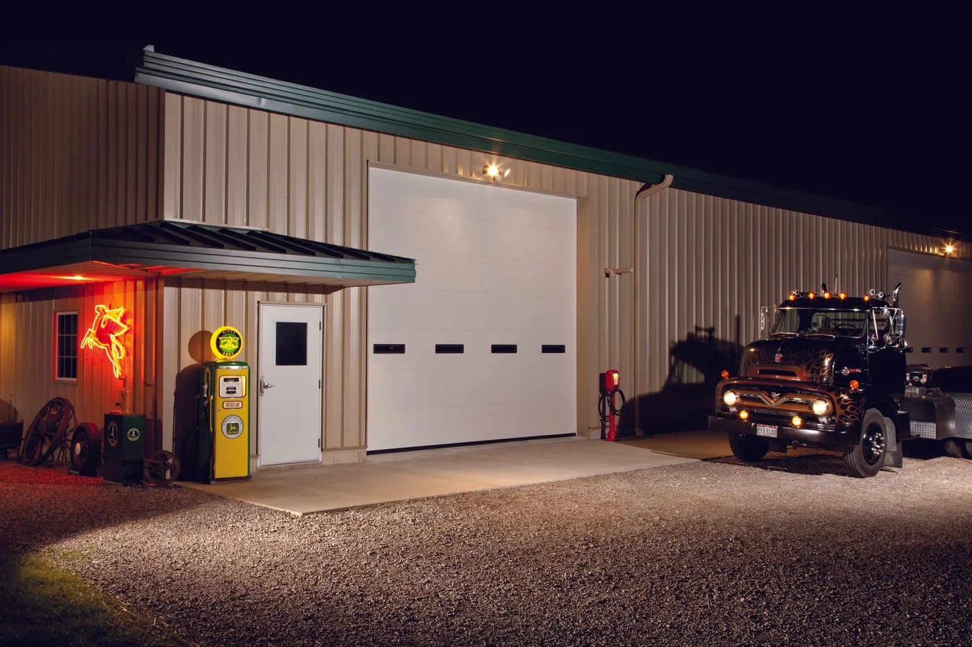 A commercial shop door lit at night with equipment inside