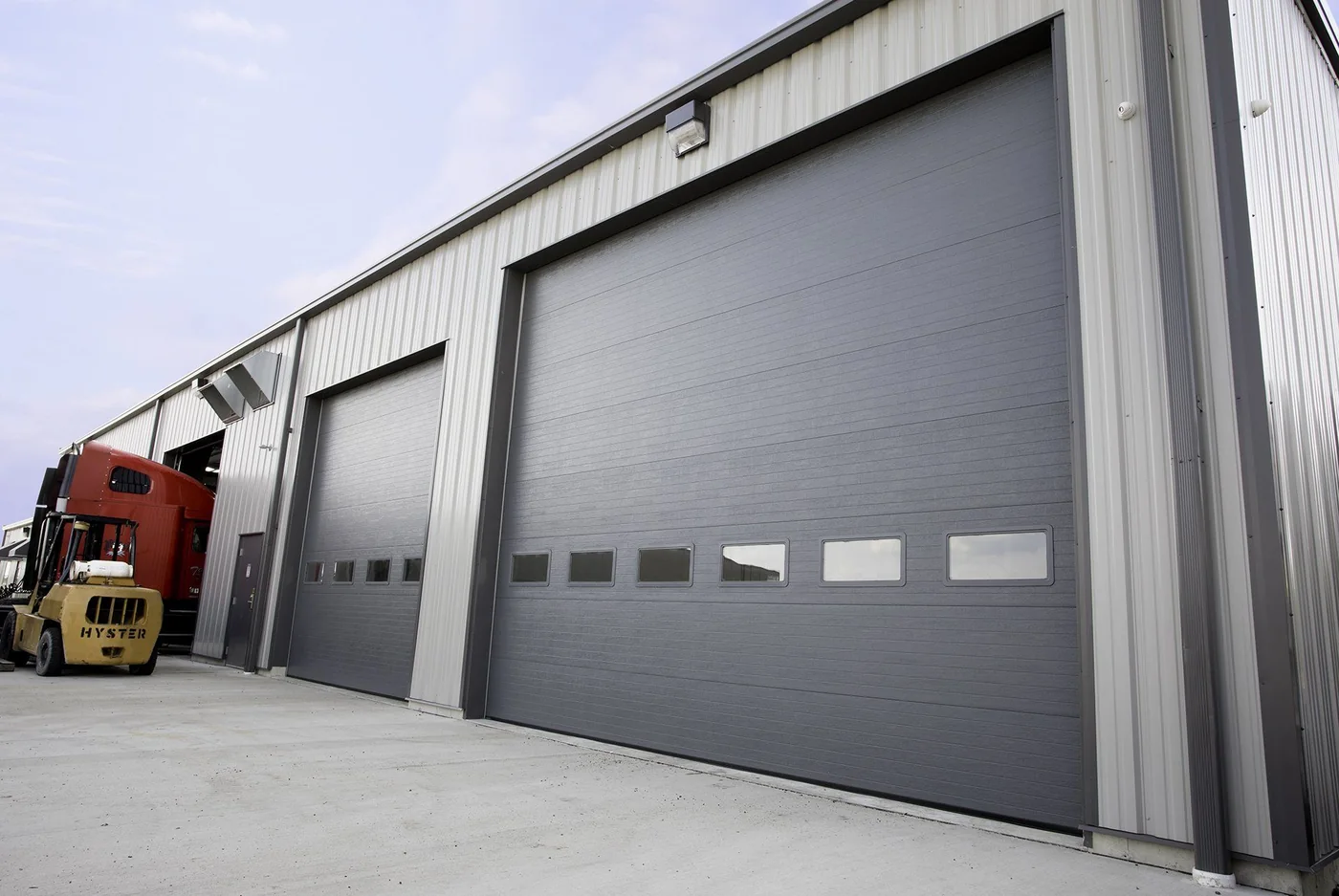 A wide white commercial door on a workshop building