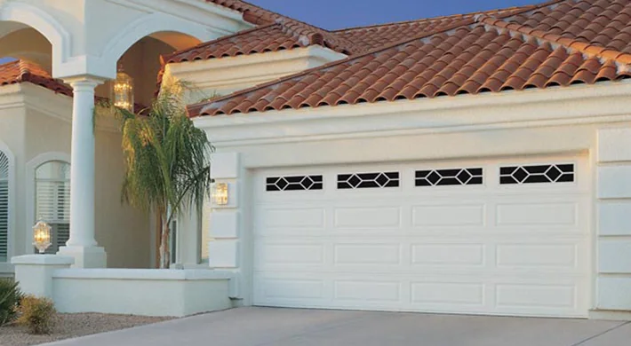 An arched stucco garage entry with a white door and palms