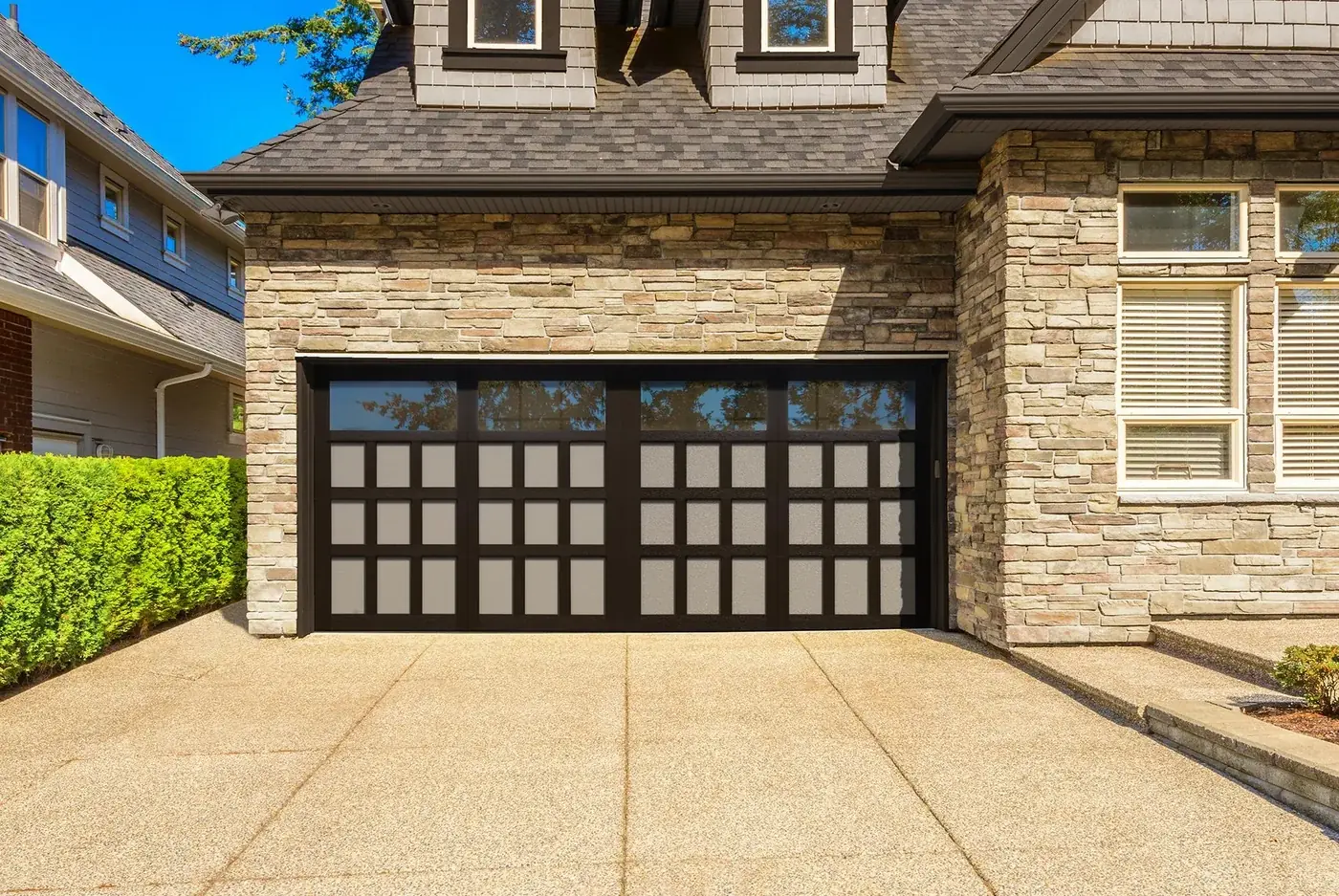 A stone faced Florida home with a black full view glass garage door