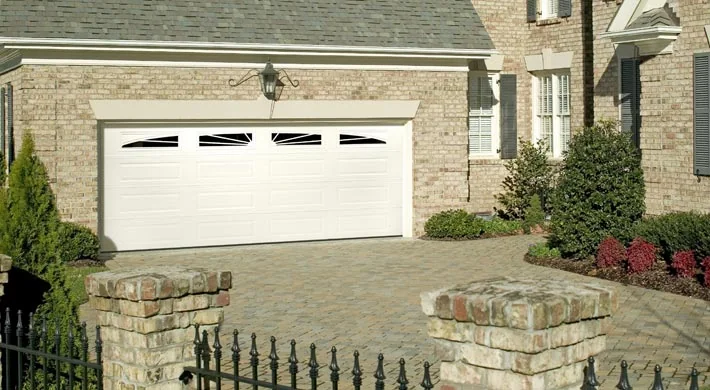 A tile roof home with a white garage door and a palm