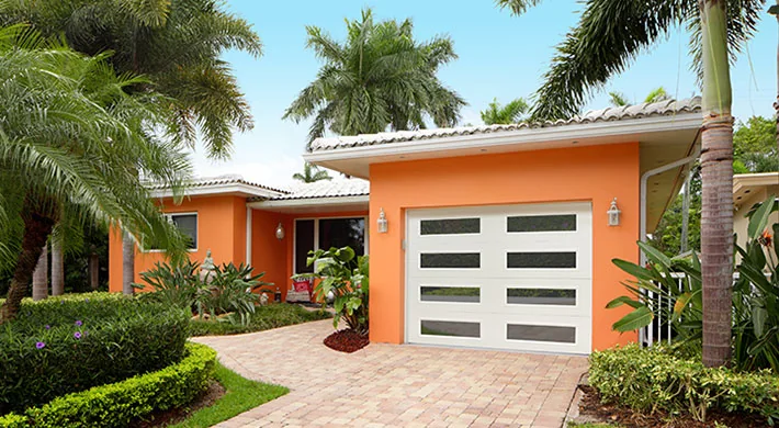 A stucco Florida home with a white garage door behind planting