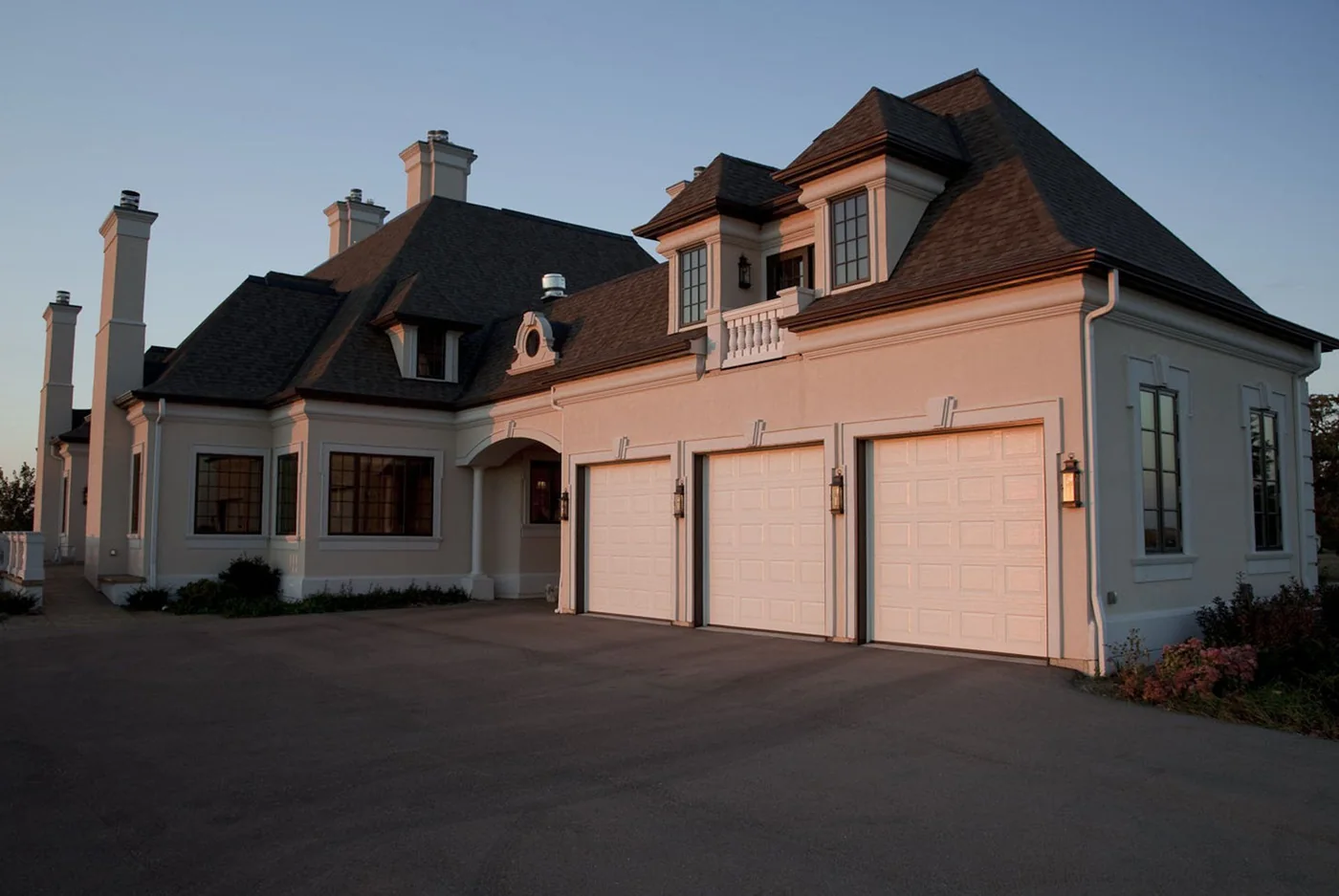 A pink Mediterranean home with two white garage doors