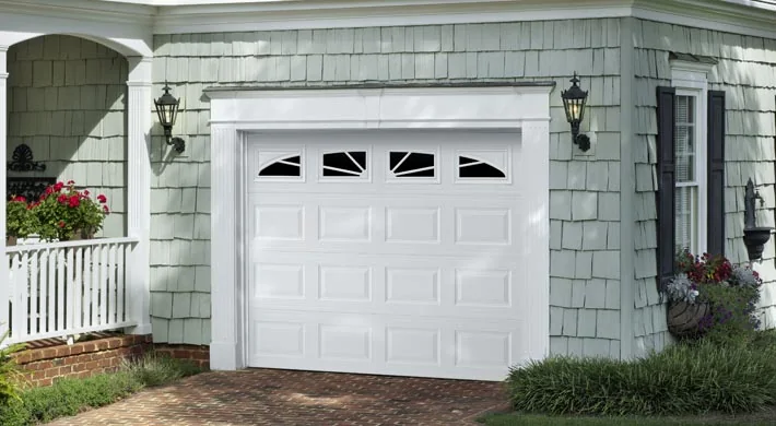 A white carriage style garage door with window inserts on a coastal home