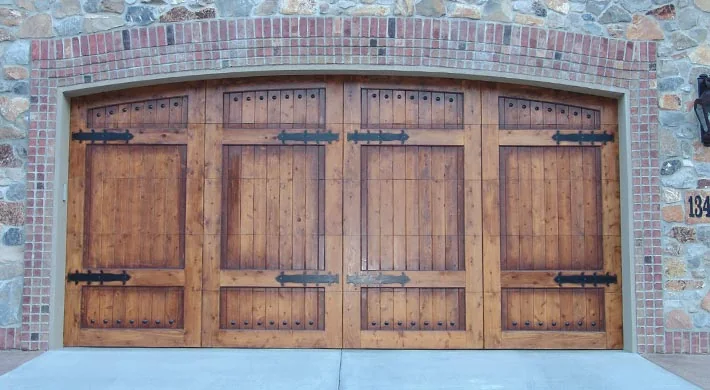 A terracotta Mediterranean home lit at sunset with wood garage doors