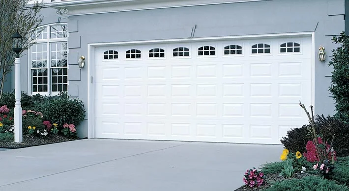 A tan garage door with arched windows on a Mediterranean home