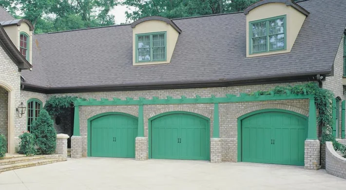 Two teal green garage doors on a pale stucco home