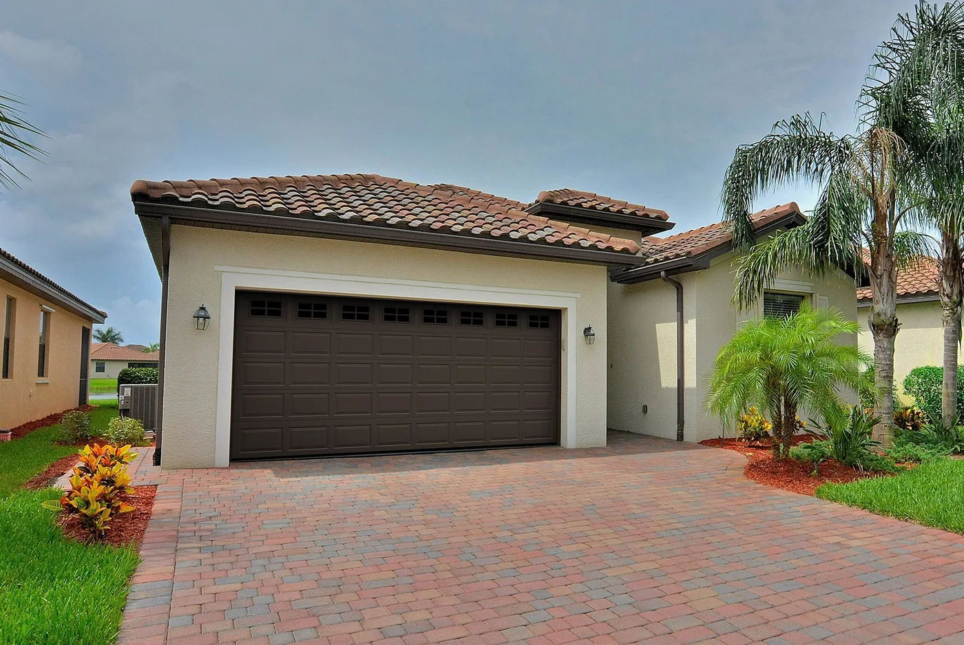 A barrel tile roof Florida home with an arched entry and a dark garage door