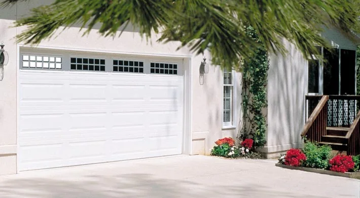 A white double garage door on a Florida home with mature palms