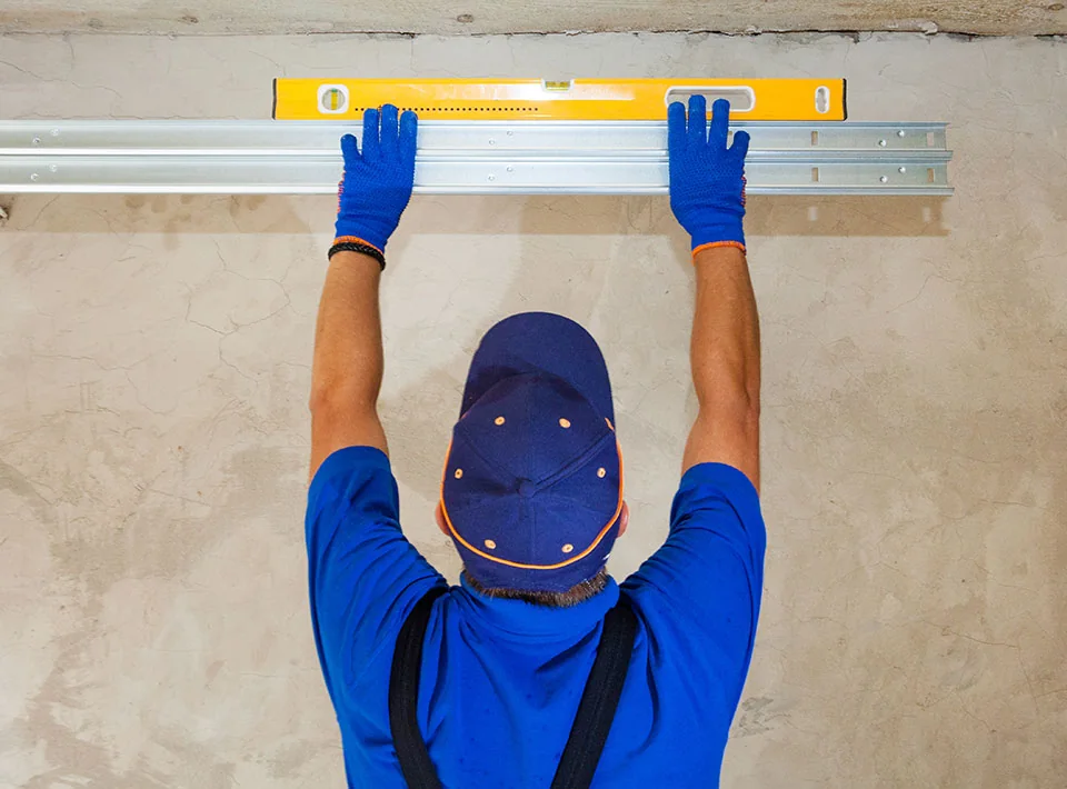 An installer checking a garage door header with a level
