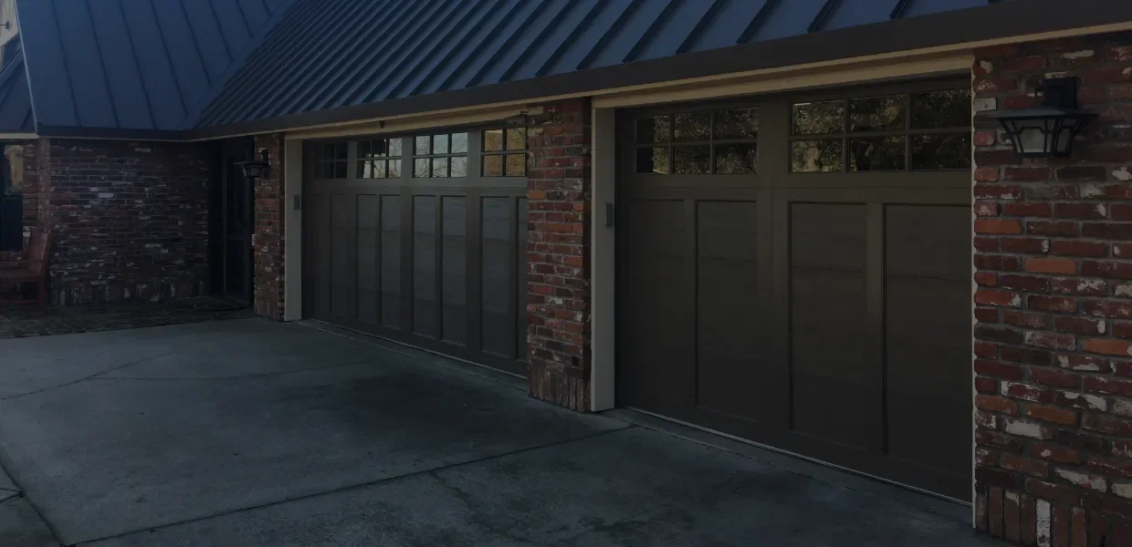 A bronze framed full view glass garage door in a modern entry court