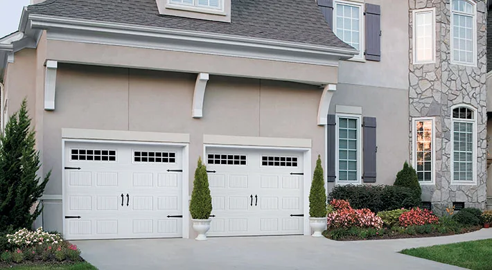Two full view glass garage doors glowing at night on a modern home