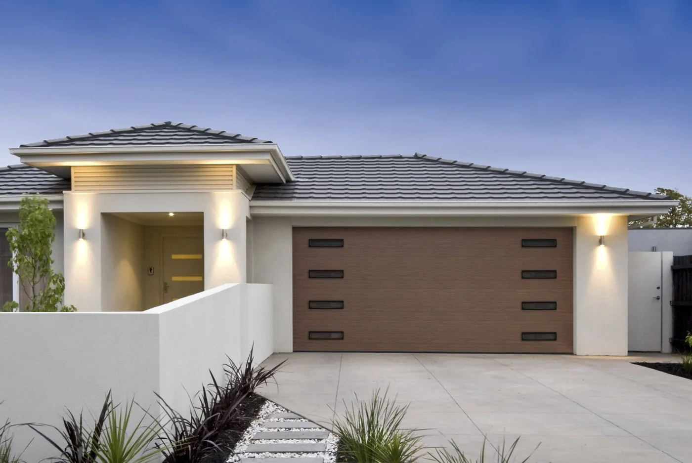 A modern white stucco home with a wood flush panel garage door