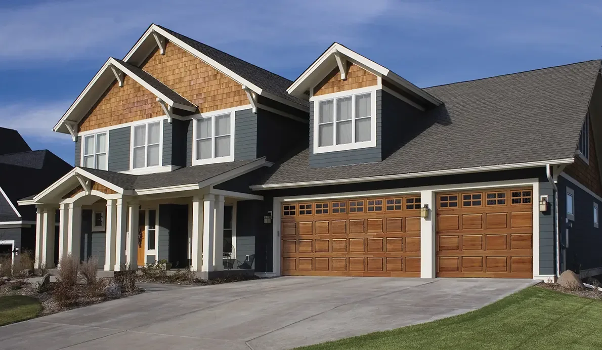 A modern white home with a dark full view aluminium garage door