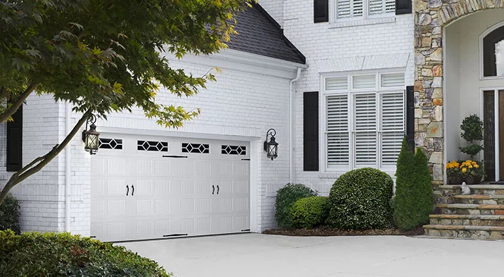 A plain white flush garage door on a white modern house