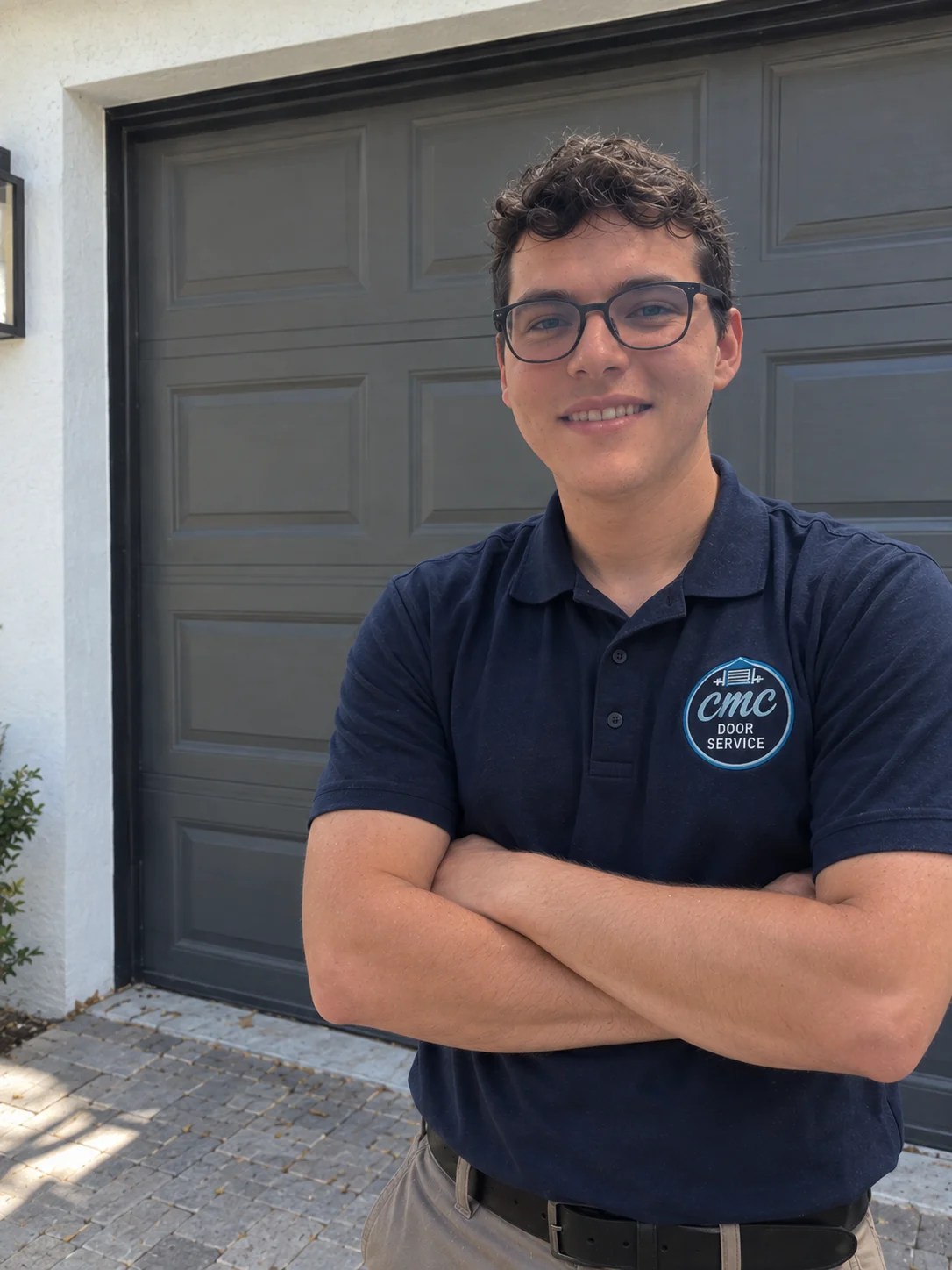 Christian Esparragoza, owner of CMC Door Service, in a company polo in front of a dark garage door in Miami
