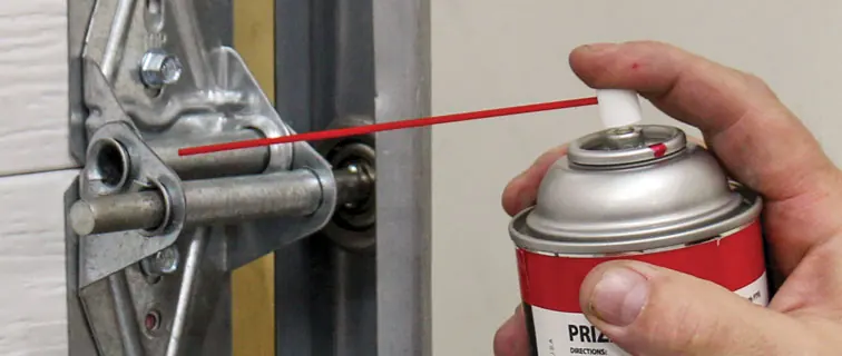 Silicone lubricant being sprayed onto a garage door roller stem and hinge