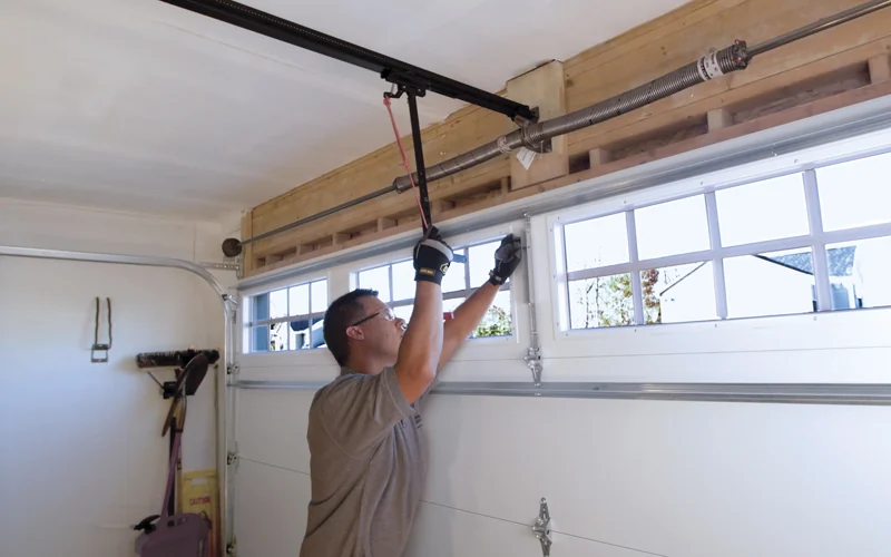 Technician working on the rail and trolley of a ceiling mounted garage door opener