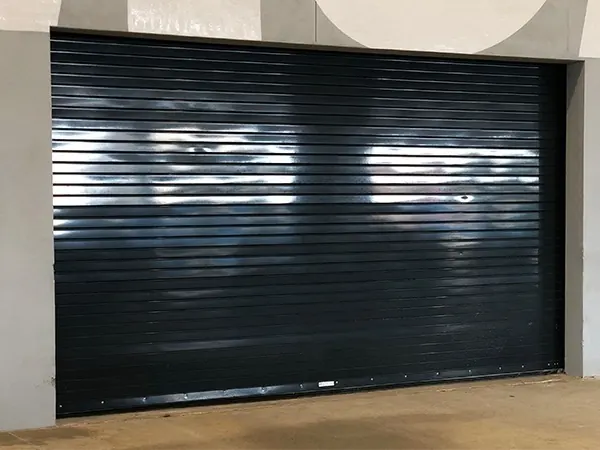 A black steel rolling door closed in a white wall opening