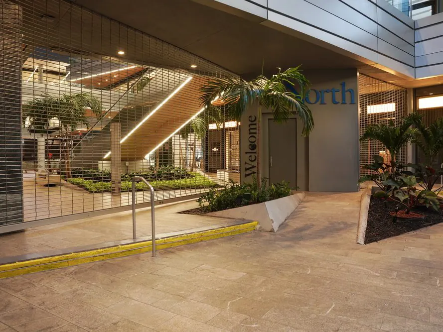A rolling security grille closing off a building atrium with planters and a staircase