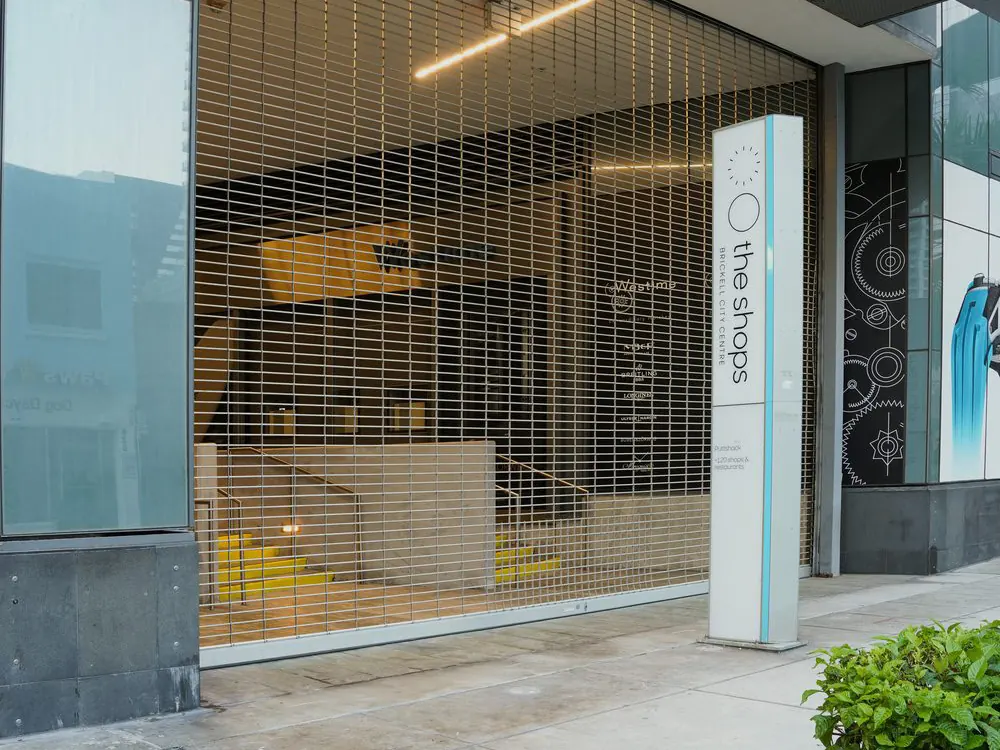 A rolling security grille across the glass entrance of an office tower lobby