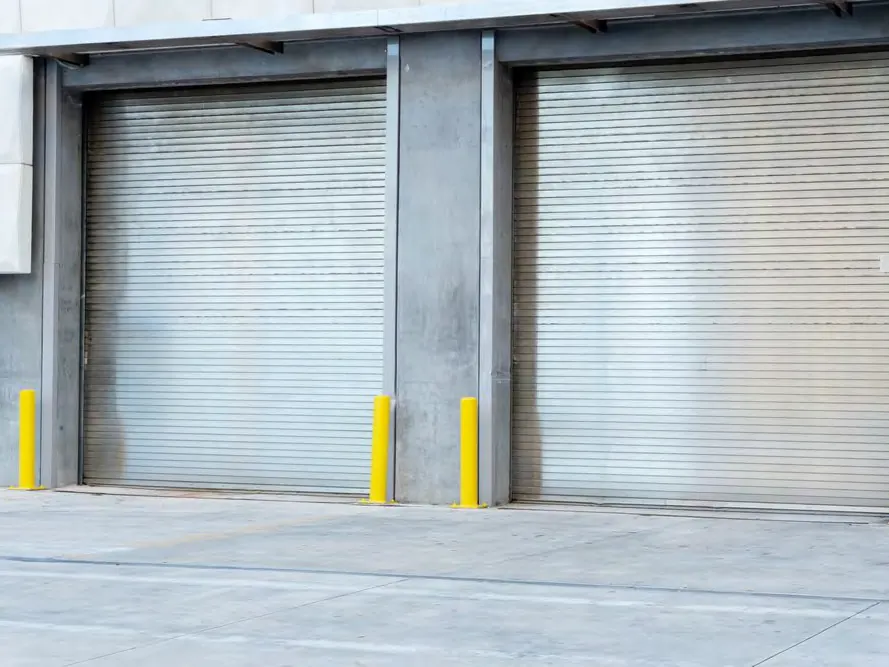 Dos puertas enrollables aisladas cerradas lado a lado en una fachada de concreto