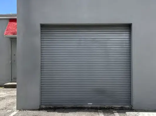 Una puerta enrollable aislada cerrada en un edificio gris de bloque