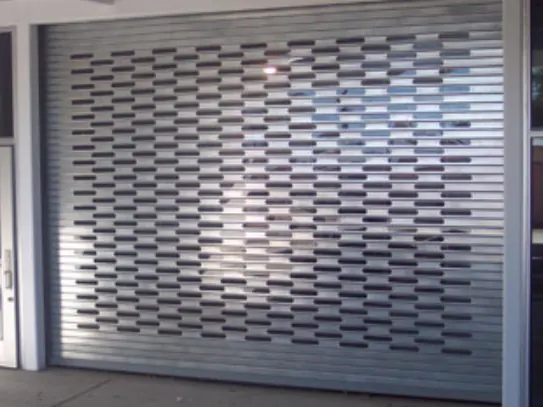 A perforated steel rolling door closed over a shop front