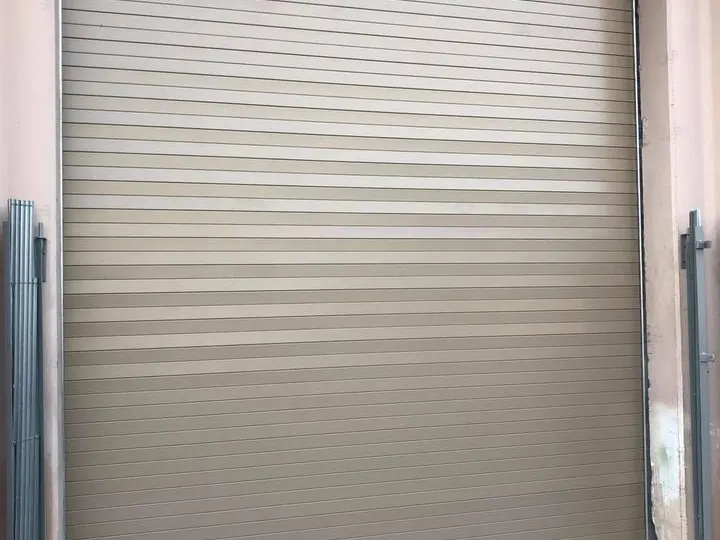 A tan steel rolling service door closed in a warehouse bay